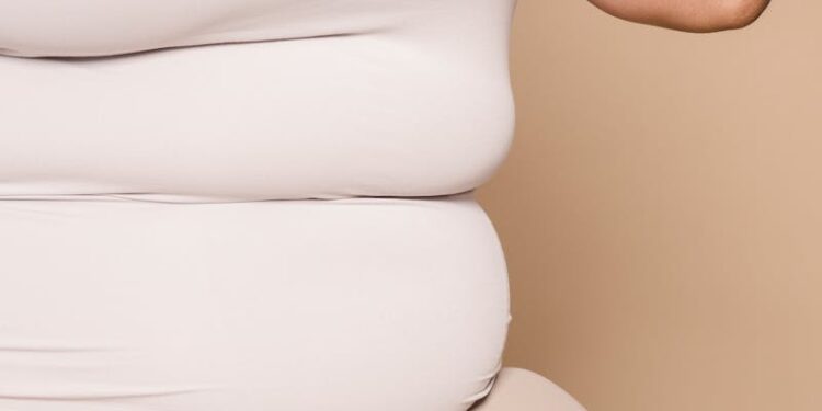Faceless overweight woman in light clothes