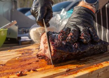 a man cutting up a piece of meat on a cutting board