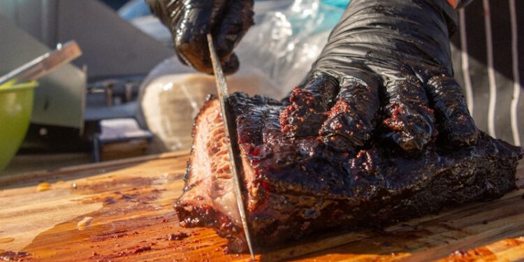 a man cutting up a piece of meat on a cutting board