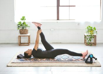 woman in black tank top and black leggings lying on black and white floral area rug
