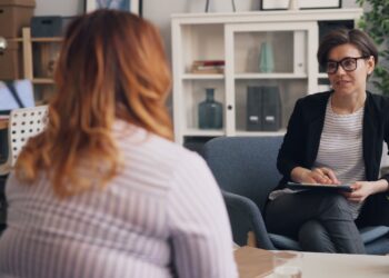 A woman sitting in an office talking to another woman