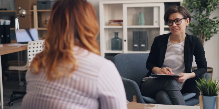 A woman sitting in an office talking to another woman