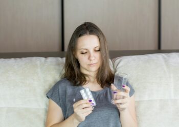 a woman sitting on a couch looking at her cell phone