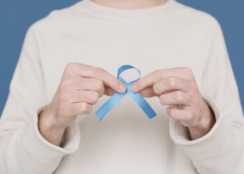 A person holding a blue awareness ribbon symbolizing support for various causes.