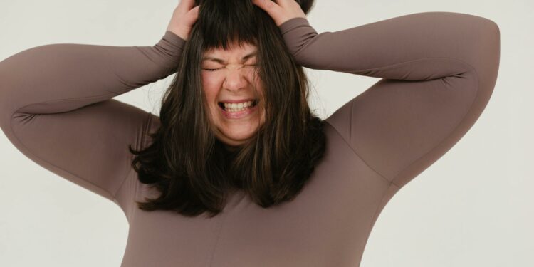 young obese woman rumpling hair with closed eyes in white studio