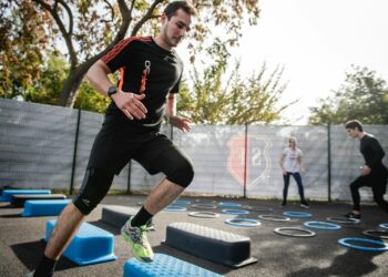 man in black crew neck t-shirt and black shorts running on blue and white trampoline
