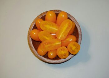 a wooden bowl filled with lots of orange tomatoes