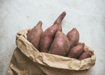 a brown paper bag filled with sweet potatoes