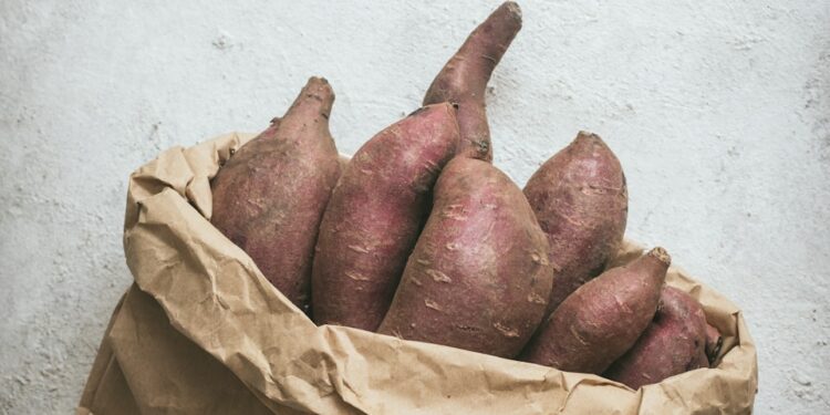 a brown paper bag filled with sweet potatoes