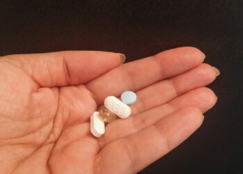 person holding four assorted medicine tablets