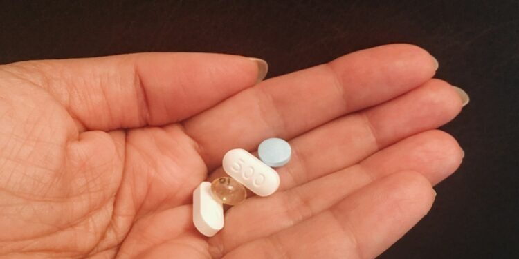 person holding four assorted medicine tablets