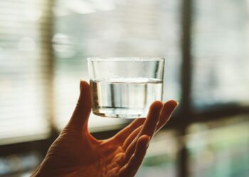 person holding clear glass cup with half-filled water