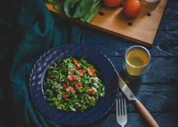 vegetable salad in bowl with fork, knife, and glass