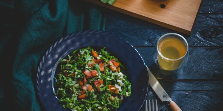 vegetable salad in bowl with fork, knife, and glass