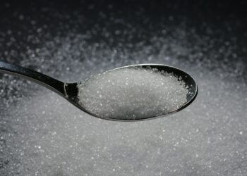 a spoon filled with sugar on top of a table