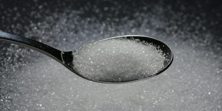 a spoon filled with sugar on top of a table