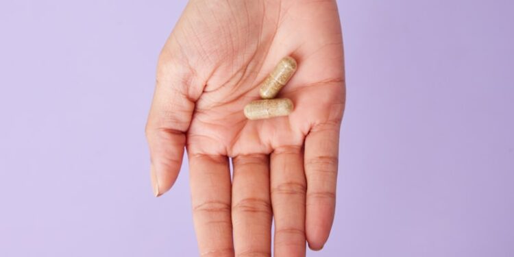 A person holding a pill in their hand