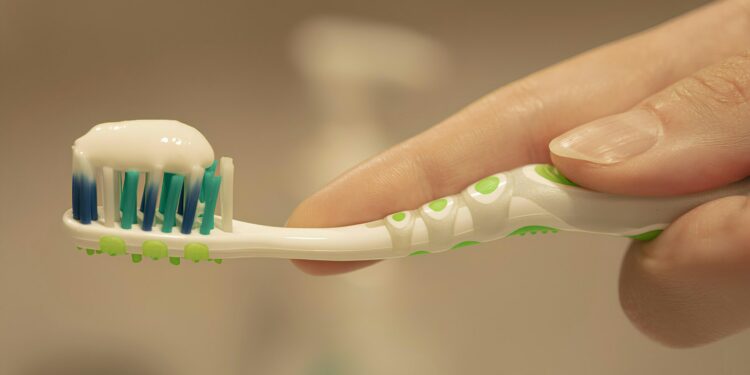 a person is holding a toothbrush with toothpaste on it