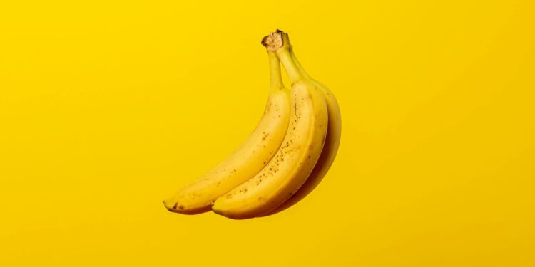 A bunch of ripe yellow bananas against a vivid yellow backdrop, offering tropical freshness.