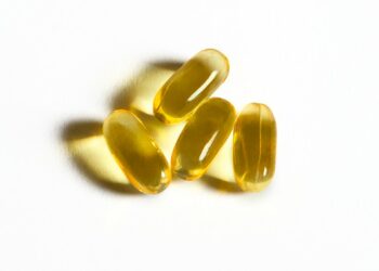Four yellow capsules sit on a white surface.