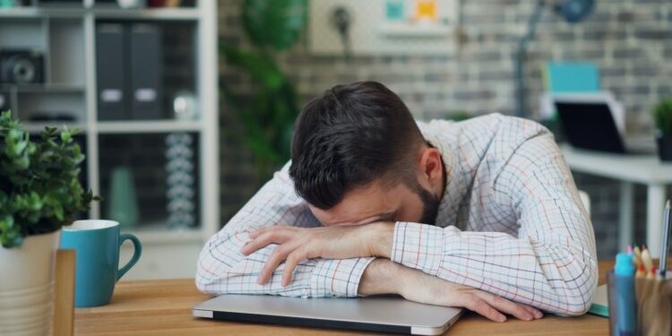 a man sitting at a desk with his head in his hands