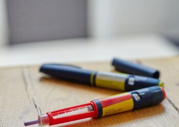 a couple of insulin pens sitting on top of a wooden table