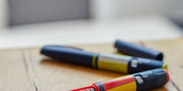 a couple of insulin pens sitting on top of a wooden table