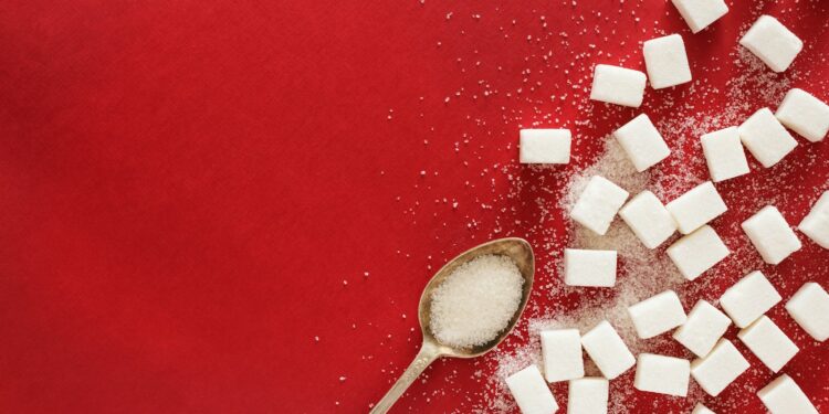 sugar cubes and a spoon on a red surface