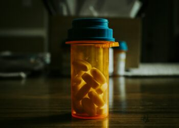a bottle filled with pills sitting on top of a wooden table