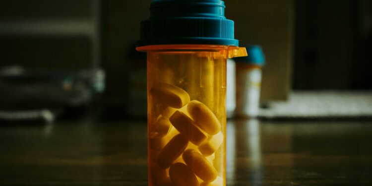 a bottle filled with pills sitting on top of a wooden table