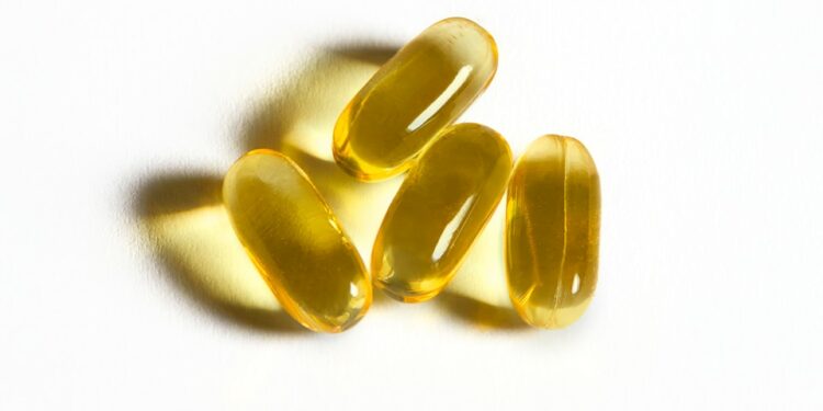 Four yellow capsules sit on a white surface.