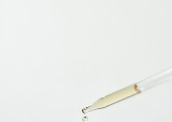 Close-up of a brown glass dropper bottle with a droplet, perfect for essential oils or medicine use.