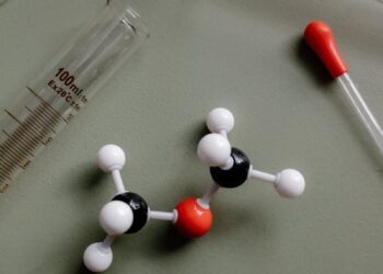 Close-up of a molecular model surrounded by laboratory equipment like pipettes and test tubes.